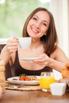 Photo of young caucasian woman having breakfast at home