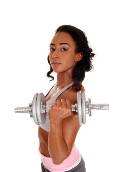 A beautiful young African American woman in a gray sports bra and shorts, exercising with dumbbell’s, isolated for white background.