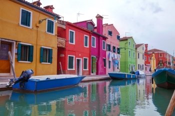 BURANO, ITALY - NOVEMBER 23: Brightly painted houses at the Burano canal on November 23, 2015 in Burano, Venice, Italy. It’s an island in the Venetian Lagoon, northern Italy.