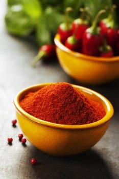 Paprika in a bowl and hot chili peppers on vintage background