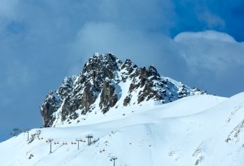 Winter rocky mount top (Tyrol, Austria) and ski lift on slope.