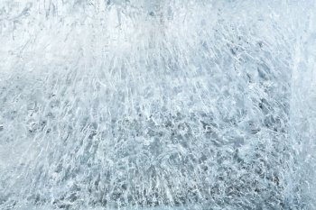Glacial transparent wall of ice with interesting drawings and patterns . Closeup, background.