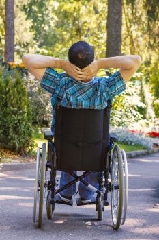 young man in a wheelchair enjoying fresh air in city park
