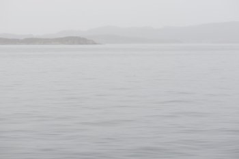 Seascape in Greenland on a foggy day with mountains, rain and calm water