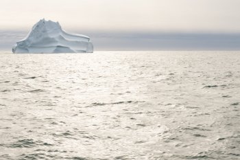 Sea and ocean landscape in greenland with dramatic sky, sun light, and iceberg