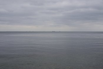 Baltic seascape with ship in distance. Baltic seascape with ship in distance and grey clouds as seen from the coast of Denmark north of Copenhagen towards Sweden