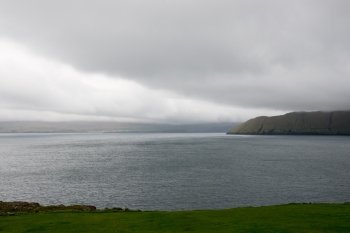 Typical landscape on the Faroe Islands as seen from Kirkjubour with green grass, mountains and sea