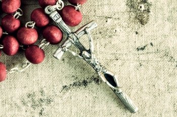 Catholic rosary on old dirty canvas background