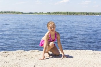 Photo of girl on the riverbank in pink swimsuit