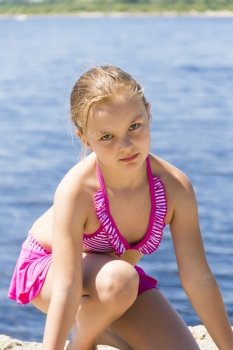 Angry girl on the riverbank in pink swimsuit