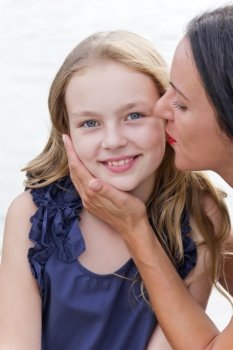 Kissing Caucasian mother and blond daughter with long hairs