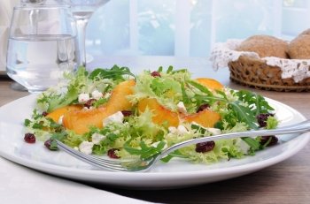 Salad of lettuce and arugula with peaches, feta cheese, cranberries