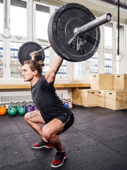 Photo of a young man at a crossfit gym lifting a barbell.