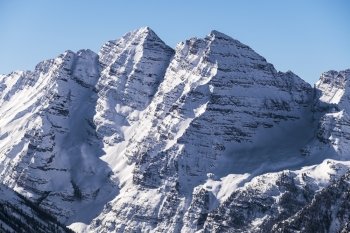 A close-up view of the mountains of the snow-covered Maroon Bells as seen from the top of Aspen Highlands in Colorado on a sunney winter day.