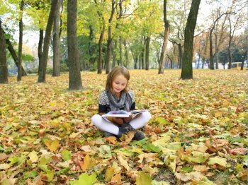 young girl reads a book in the autumn park. young girl reads a book in the autumn park sitting on the ground