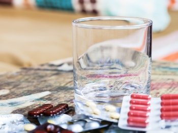 empty glass and pile of pills close up on table in living room