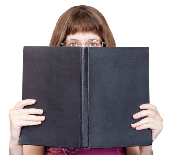 front view of girl with spectacles looks over big book with blank cover isolated on white background