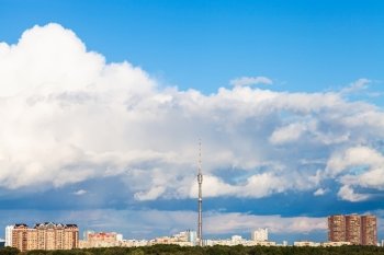 large low white cloud in blue sky over city with TV tower in summer day