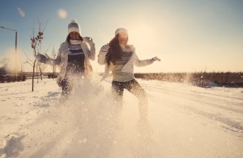 Two girlfriends have fun and enjoy fresh snow at beautiful winter day