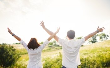 Couple standing in the field hands up, summer outdoor