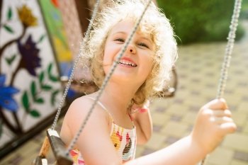 Happy girl having fun on a swing on summer day