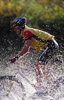 A young man cycling in a stream