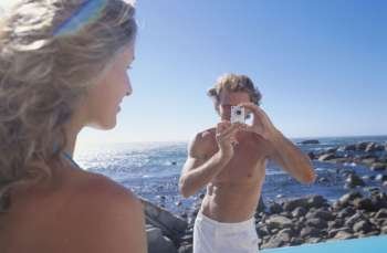 Young man taking a photograph of a young woman
