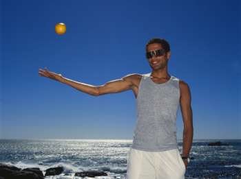 Portrait of a young man throwing a ball in the air
