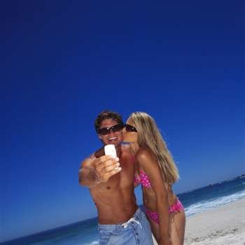 Young woman kissing a young man on the beach