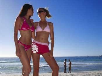 Low angle view of two young women standing on the beach