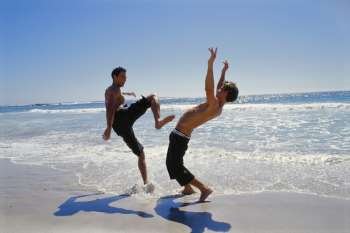 Two young men jumping on the beach