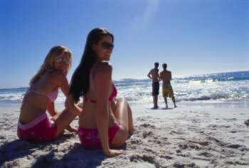 Rear view of two young women sitting on the beach