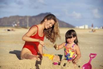 Mother Building Sandcastle With Daughter