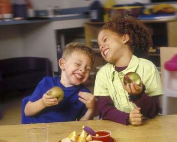 Children Eating Apples And Laughing In Classroom
