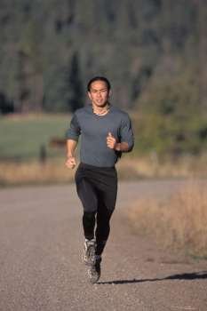 Asian American Man Jogging Through The Countryside On A Dirt Road