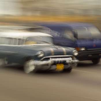 Blurred view of a car and a van on a road, Havana, Cuba