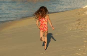 Rear of a young girl (6-8) running on a beach, Moorea, Tahiti, French Polynesia, South Pacific