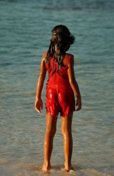 Rear of a young girl (8-9) standing on a beach, Moorea, Tahiti, French Polynesia, South Pacific