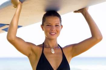 Portrait of a young woman carrying a surfboard