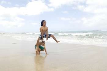 Two young men playing leapfrog on the beach