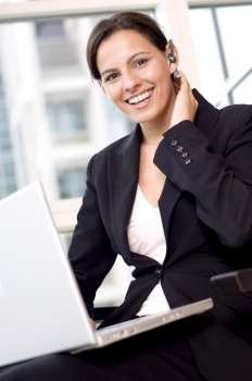 Portrait of a businesswoman sitting with a laptop on her lap and smiling