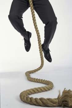 Low section view of a man climbing a rope