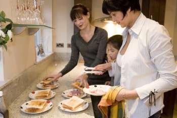 Mid adult woman with her two daughters preparing sandwiches