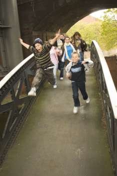 Teenage boys and teenage girls running on a bridge