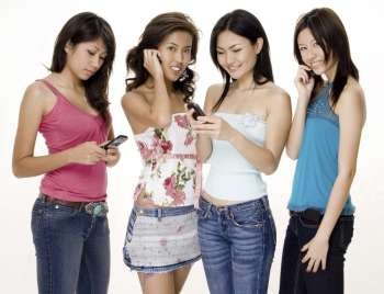 Four young women using mobile phones