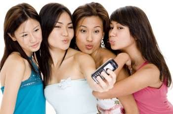 Four young women taking a picture of themselves with a mobile phone
