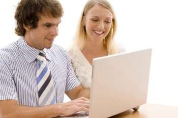 Businessman and a businesswoman looking at a laptop and smiling