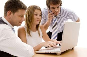 Businesswoman and two businessmen looking at a laptop