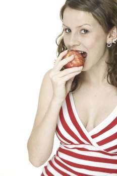 A pretty young woman in a red and white stripy top eats a red apple