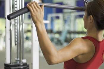 A woman demonstrates a lat pulldown exercise in a gym